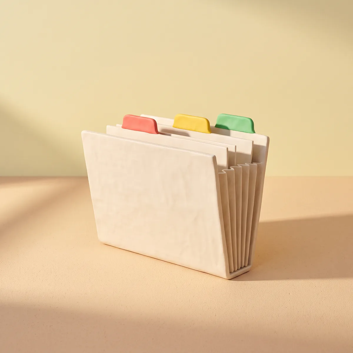 Classeur en pâte à modeler aux onglets rouge, jaune et vert, sur fond jaune pâle.