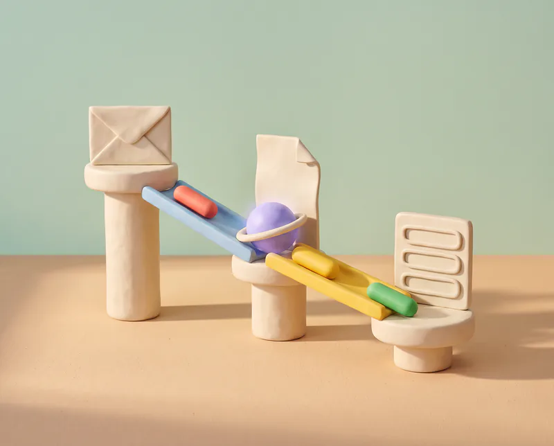 Un parcours en pâte à modeler : une enveloppe sur un premier socle, une rampe bleue où roule une pilule rouge, une sphère lavande à la jonction, puis une rampe jaune où la pilule devient verte et rejoint un petit tableau.