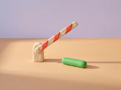 Une barrière levante en pâte rayée de rouge, ouverte, une pilule verte posée juste après.
