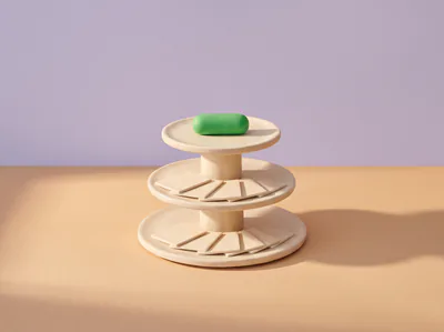 Un présentoir à trois plateaux en pâte, des cartes crème disposées en éventail sur les étages, une pilule verte au sommet.