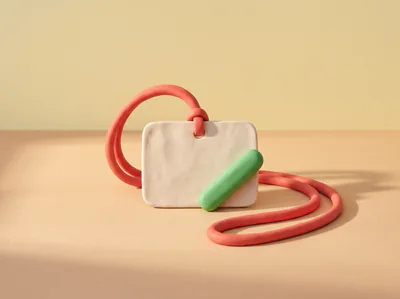 Un badge d’événement vierge en pâte au bout d’un cordon rouge, une pilule verte posée en travers.