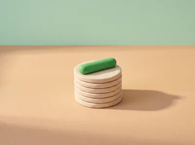 Une pile de pièces en pâte, une pilule verte posée en travers du sommet.